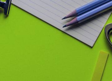 Stifte, Schere, Papier auf grünen Hintergrund